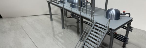 Vue latérale de la maquette de plateforme réalisée sur mesure par 3D Printlab pour un client à Tignieu (38). Cette vue montre la structure et les détails techniques de la plateforme à l’échelle réduite, illustrant la précision et le soin apportés à la conception et à l’impression 3D pour une présentation au salon Global Industrie à Lyon. Maquette miniature de plateforme réalisée en 3D par 3D Printlab pour un client de Tignieu (Isère), vue en plongée, destinée au salon Global Industrie à Lyon.